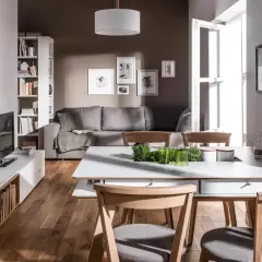 Nowoczesny salon z szarą kanapą i drewnianymi meblami. Dominują kolory brąz i szary, tworząc przytulną atmosferę.
