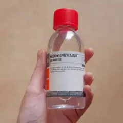 Dłoń trzyma butelkę z medium opóźniającym do farb akrylowych. To rozwiązanie, by farba akrylowa czym rozcieńczyć, by dłużej pozostała mokra.