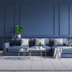Nowoczesny salon z sofą w kolorze petrol blue, ozdobioną geometrycznymi poduszkami. Ściany w tym samym odcieniu tworzą spójną, elegancką całość.