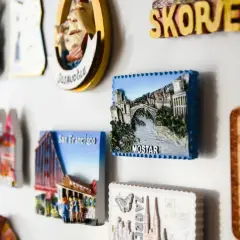 Kolekcja **dużych magnesów na lodówkę** z widokami Mostaru, San Francisco i innych miast.