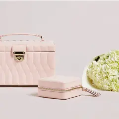 Elegancka, różowa szkatułka na zegarki i biżuterię, obok bukiet białych hortensji.