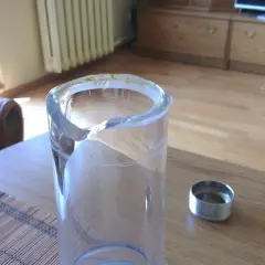 Uszkodzony szklany wazon, z którego wystają nitki kleju. Czy jedna kropelka sklei szkło? Obok metalowa obrączka.