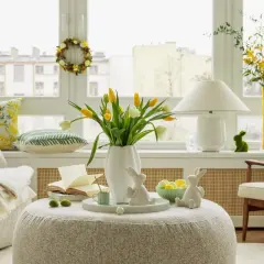 Wielkanocne ozdoby z brzozy, w tym wianek i zajączki, tworzą przytulną atmosferę. Żółte tulipany dodają wiosennego akcentu.