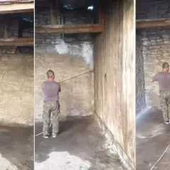 Mężczyzna wykonuje bielenie ścian w starym budynku, rozpoczynając prace od narożnika.