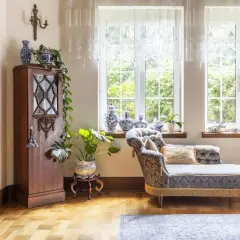 Elegancka sypialnia z meblami w stylu vintage. Drewniana szafa, ozdobna kanapa i porcelanowe wazony tworzą przytulną atmosferę.