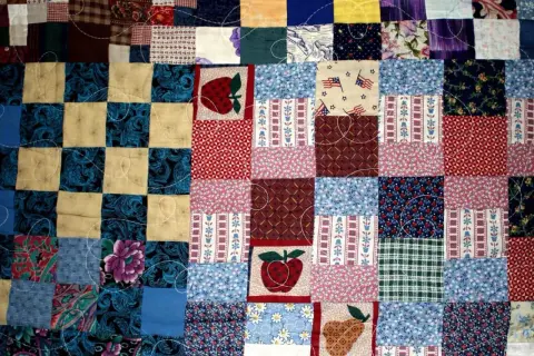 Kolorowy patchwork, czyli technika szycia z kawałków materiału, tworzy wzory z jabłkami, kwiatami i flagami USA.