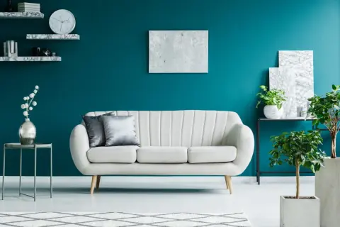 Elegancki salon z kanapą i roślinami na tle głębokiego turkus koloru ścian.