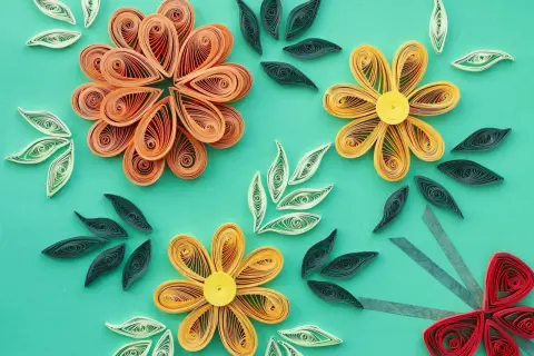 Kwiaty i liście wykonane techniką quilling. Wzory z papierowych pasków tworzą delikatne kompozycje.
