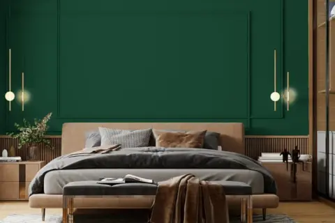 Sypialnia z łóżkiem i narzutą w odcieniu **midnight green**. Eleganckie lampy wiszące i drewniane meble tworzą przytulną atmosferę.