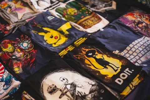 Stos koszulek z nadrukami: Iron Man, Pikachu, Jack Skellington, klawiatura. Zastanawiasz się, jak przykleić odklejający się nadruk na koszulce?