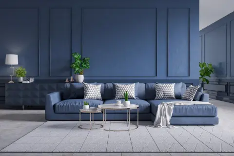 Nowoczesny salon z sofą w kolorze petrol blue, ozdobioną geometrycznymi poduszkami. Ściany w tym samym odcieniu tworzą spójną, elegancką całość.