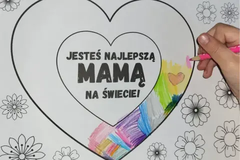Dziecko koloruje serce z napisem "Jesteś najlepszą mamą na świecie!". Wokół serca znajdują się ornamenty do druku w kształcie kwiatów.