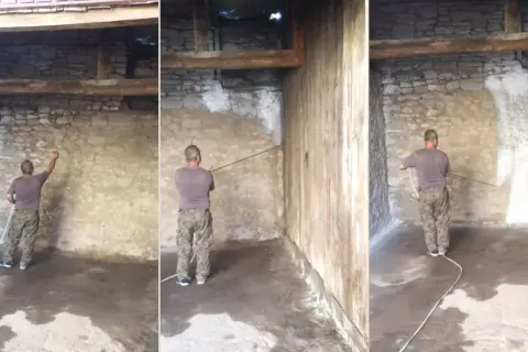 Mężczyzna wykonuje bielenie ścian w starym budynku, rozpoczynając prace od narożnika.
