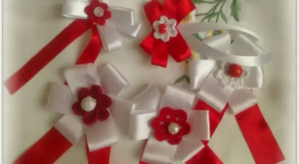 Jak zrobić kotylion ze wstążki? Piękne, ręcznie robione kotyliony z białych i czerwonych wstążek, ozdobione szydełkowymi kwiatuszkami.