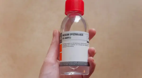 Dłoń trzyma butelkę z medium opóźniającym do farb akrylowych. To rozwiązanie, by farba akrylowa czym rozcieńczyć, by dłużej pozostała mokra.