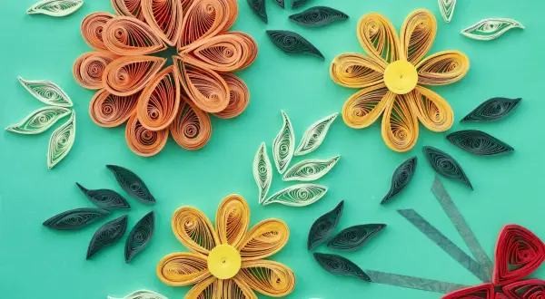 Kwiaty i liście wykonane techniką quilling. Wzory z papierowych pasków tworzą delikatne kompozycje.