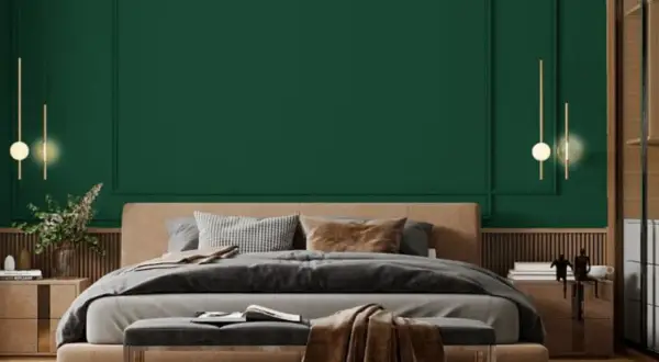 Sypialnia z łóżkiem i narzutą w odcieniu **midnight green**. Eleganckie lampy wiszące i drewniane meble tworzą przytulną atmosferę.