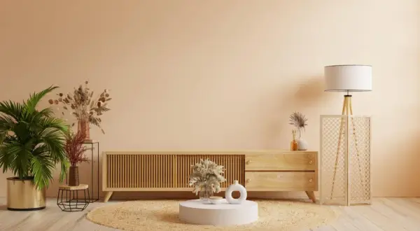 Salon w odcieniach koloru lnu. Drewniana komoda, okrągły dywan, palma i dekoracje tworzą przytulną atmosferę.
