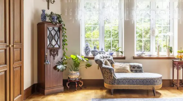 Elegancka sypialnia z meblami w stylu vintage. Drewniana szafa, ozdobna kanapa i porcelanowe wazony tworzą przytulną atmosferę.