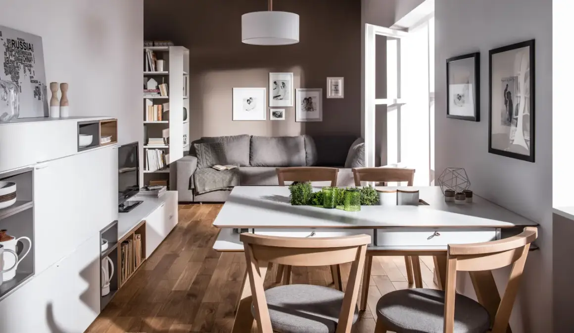 Nowoczesny salon z szarą kanapą i drewnianymi meblami. Dominują kolory brąz i szary, tworząc przytulną atmosferę.