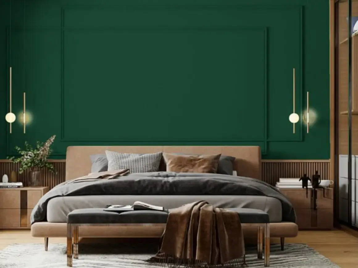 Sypialnia z łóżkiem i narzutą w odcieniu **midnight green**. Eleganckie lampy wiszące i drewniane meble tworzą przytulną atmosferę.