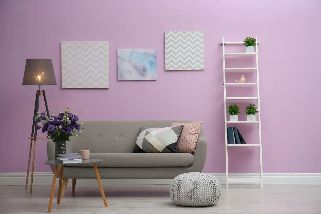 Przytulny salon z sofą, stolikiem i regałem na tle ściany w kolorze lila róż.