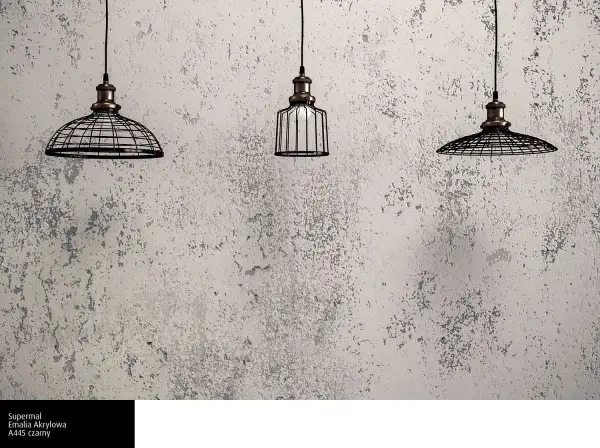 Trzy lampy wiszące w industrialnym stylu na tle ściany pokrytej betonową farbą. Ta farba nadaje wnętrzu surowy, loftowy charakter.